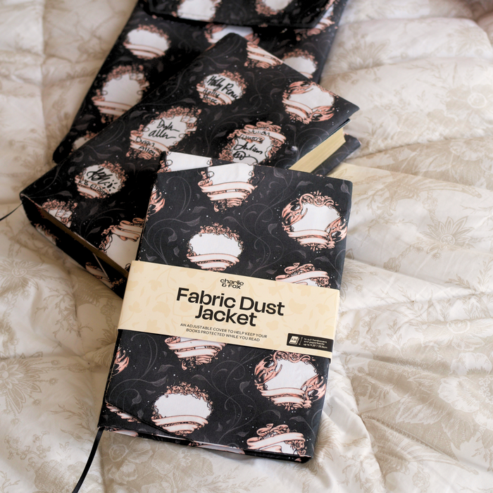 A black fabric dust jacket featuring blank book plates on top of a white blanket.