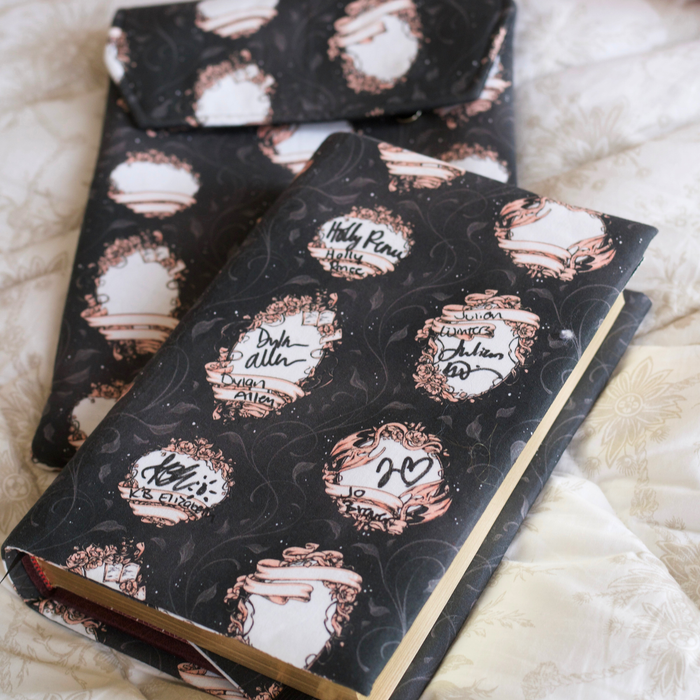 A book with  black fabric dust jacket featuring blank book plates and some with author's signatures on top of a white blanket. 